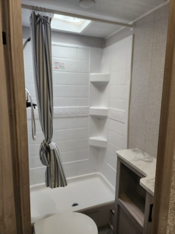 View of the full shower, toilet, and vanity in the bathroom of the 2023 Della Terra 175BHLE Bunk House